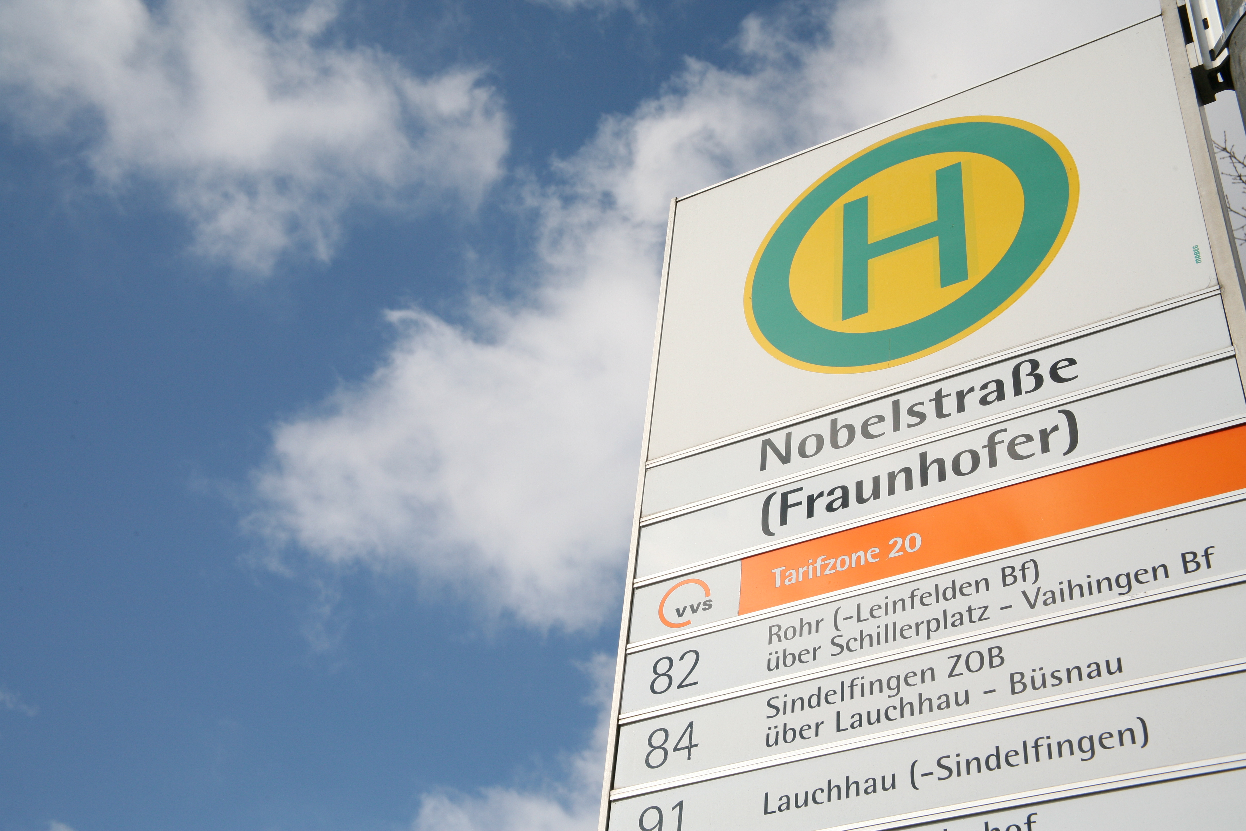 Man sieht das Schild der Bushaltestelle Fraunhofer IRB in der Nobelstraße 12 in Stuttgart vor blauem Himmel.